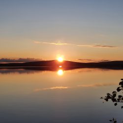 kuulas vesi, ilta-auriko paistaa tunturin takaa