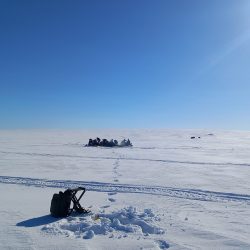 pilkkireppu ja taustalla isompi pilkkiseurue, kevät auringossa